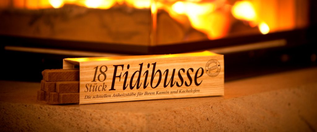 Anzünder Fidibusse in Faltschachtel vor brennendem Kamin