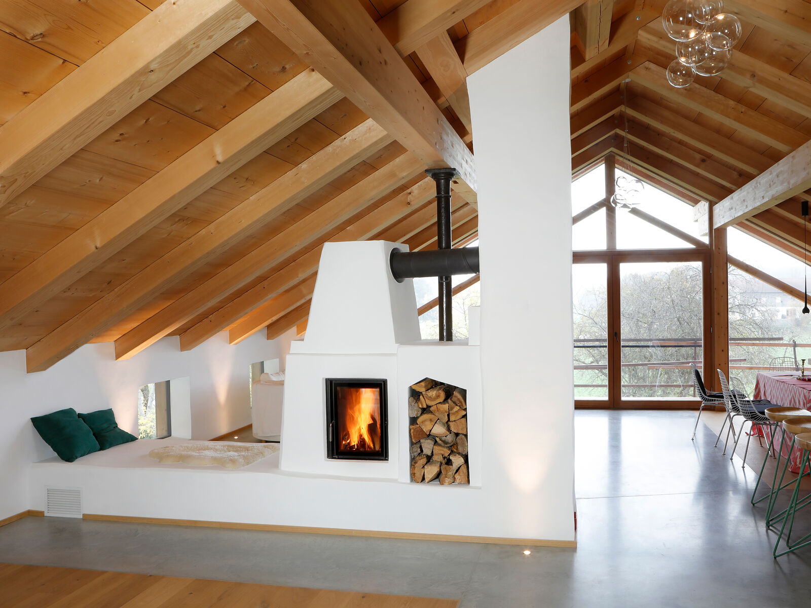 Weißer Kachelofen als Raumteiler im Dachgeschoss