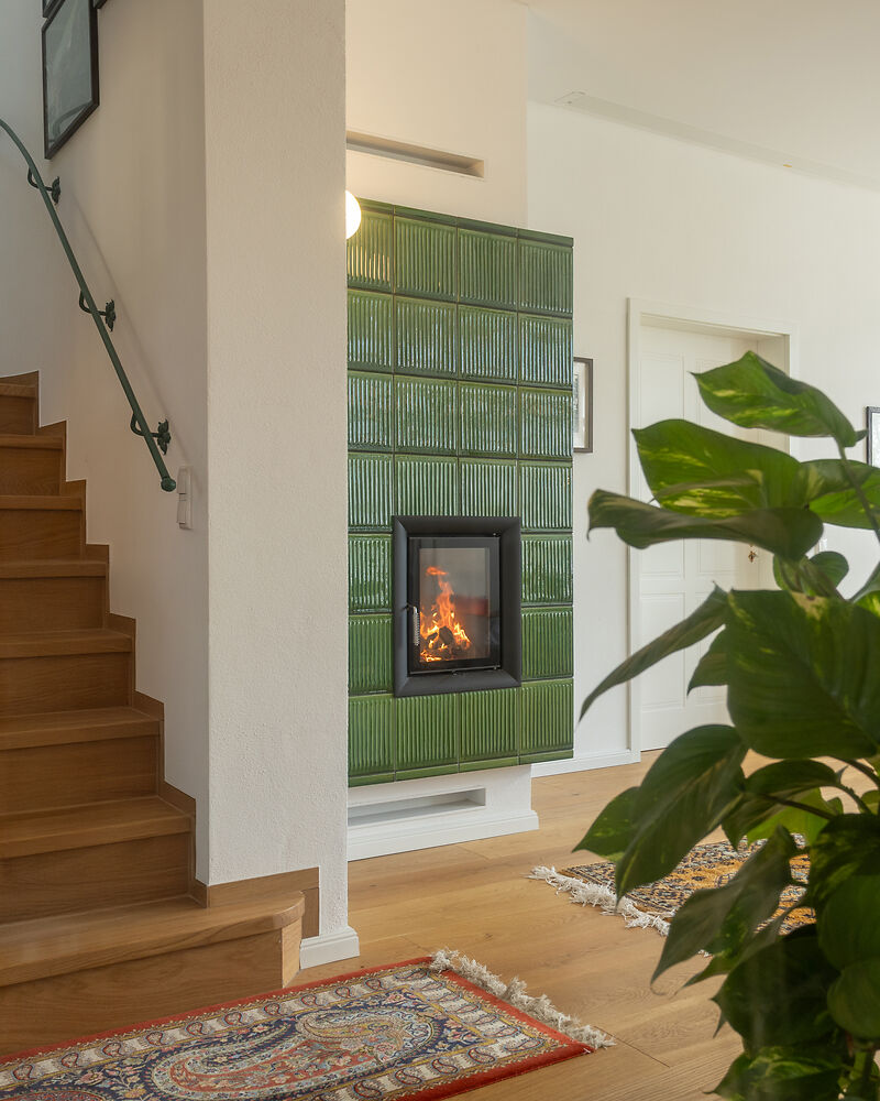 Kachelofen mit grünen Kacheln im Wohnraum