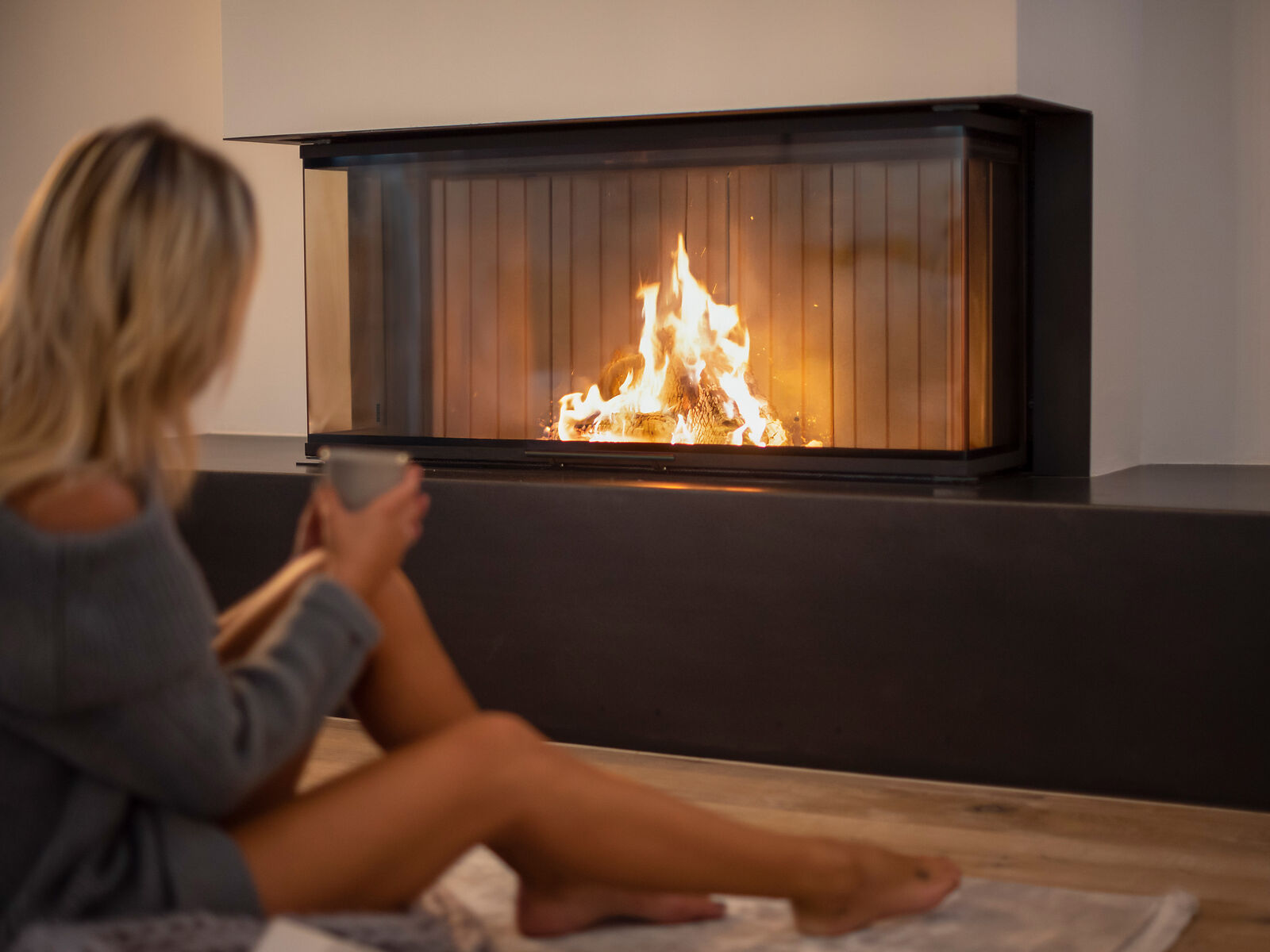 BRUNNER Kamin Panorama im Wohnzimmer mit Frau und Teetasse