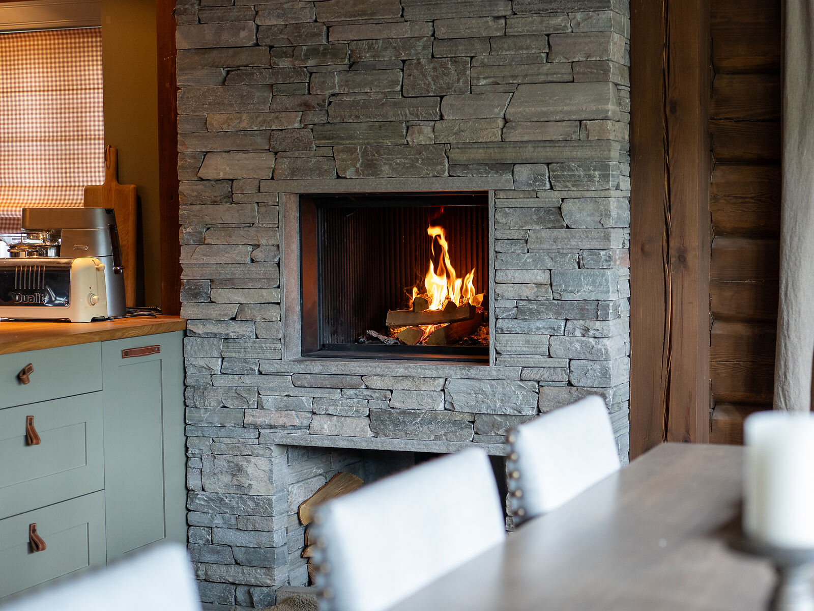 Offener, flacher Kamin in Steinwand neben der Küche verbaut