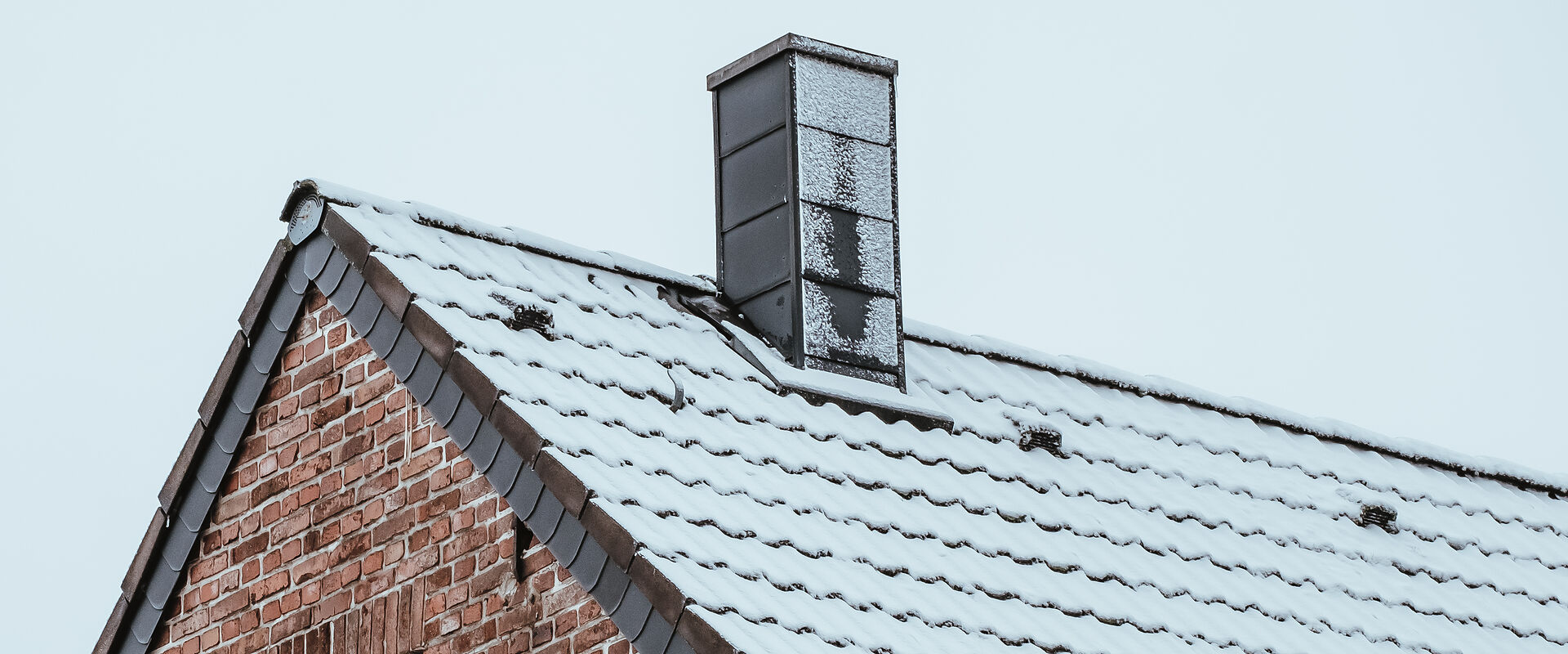 Verschneites Hausdach mit einem Schornstein