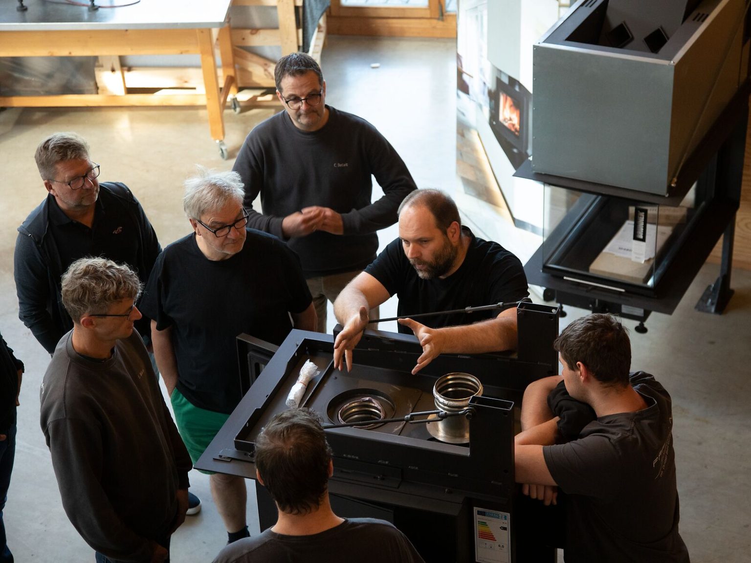 Brunner Techniker erklärt einer Gruppe von Menschen am Kamineinsatz