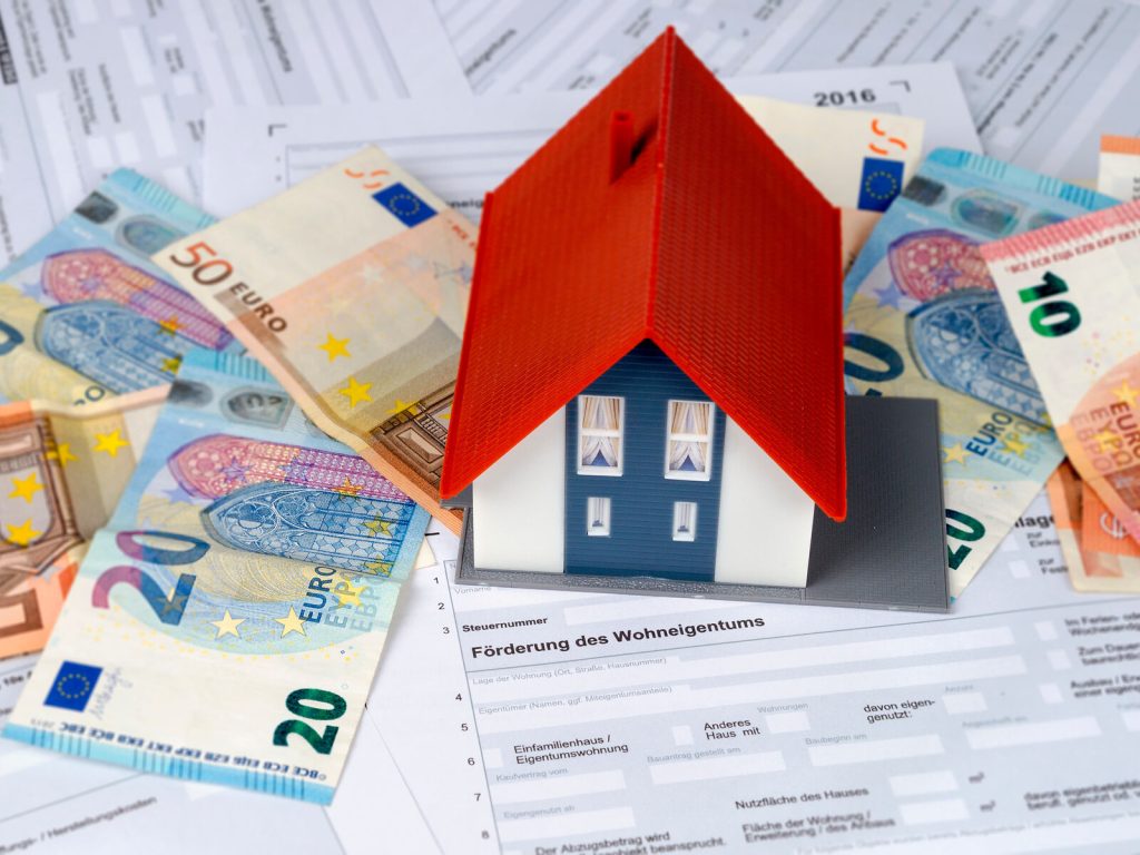 Förderungsanträge, Geldscheine und ein Hausmodell